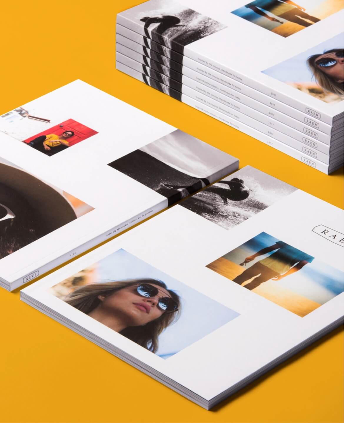 Stacks of RAEN printed lookbooks with eyewear and surf photography on a yellow surface