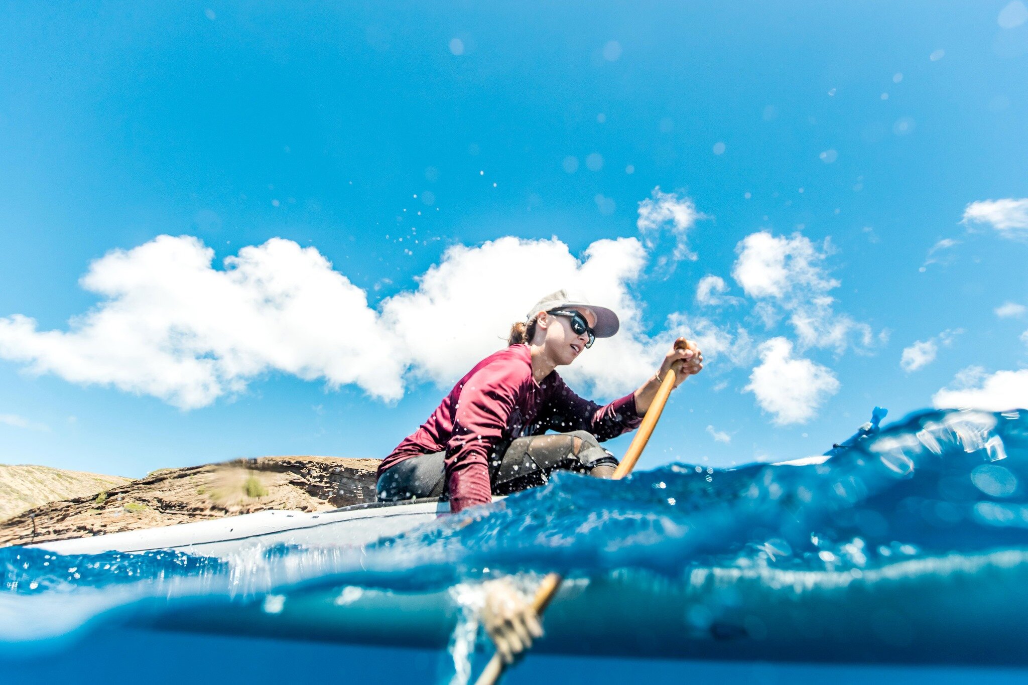 A paddler wearing Costa sunglasses on bright blue ocean water
