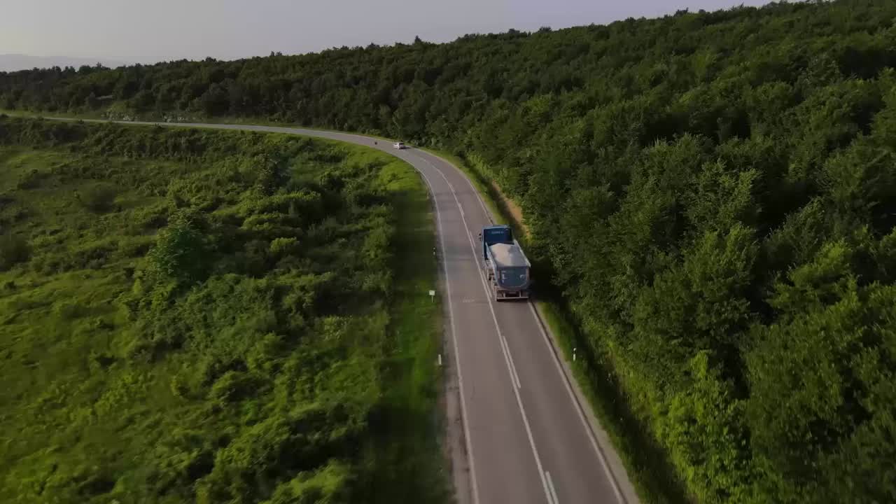 A commercial truck rounding a forest road in a LightMetrics video still