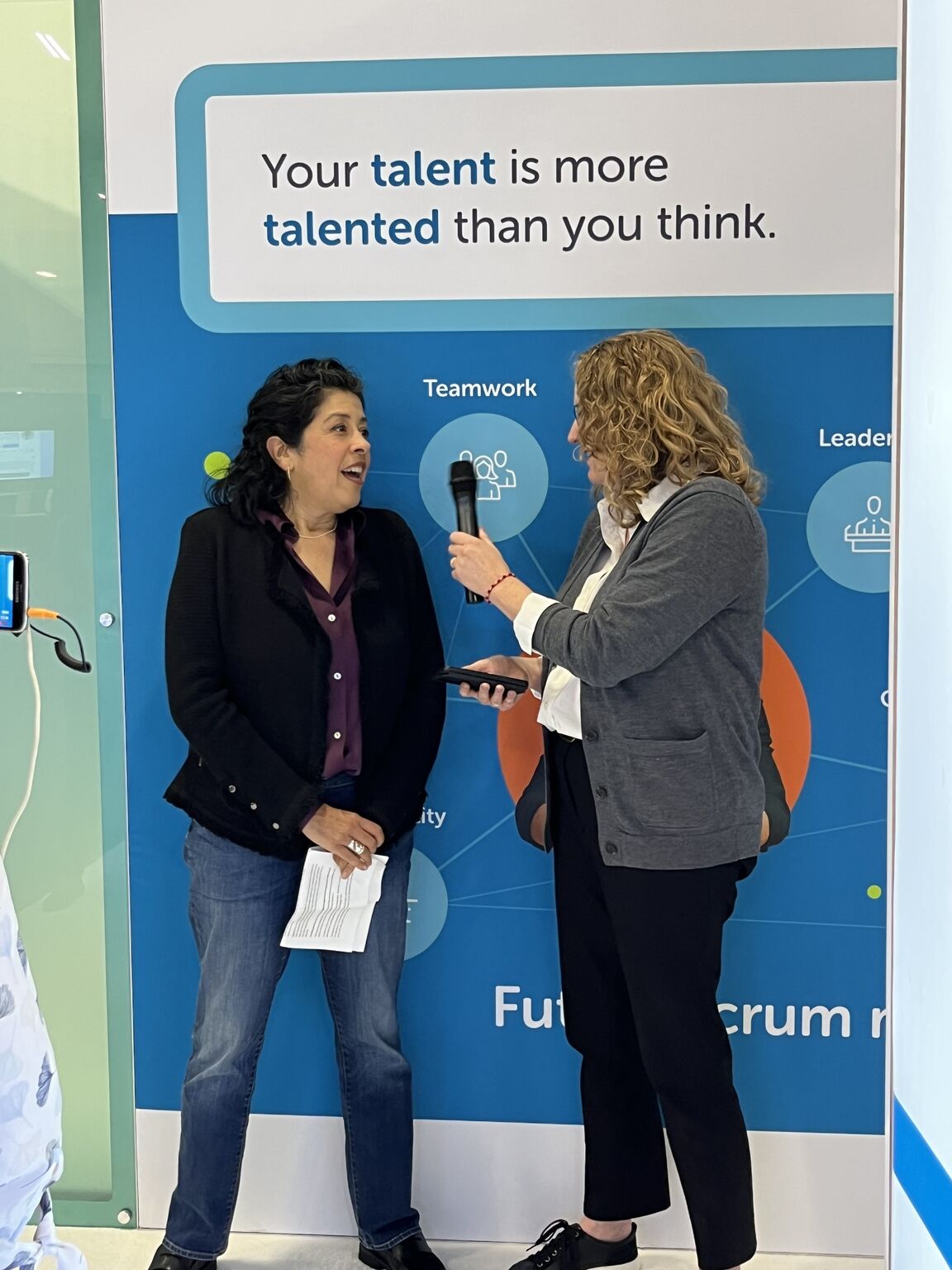 Ligia Zamora speaking with an interviewer at an HR technology event