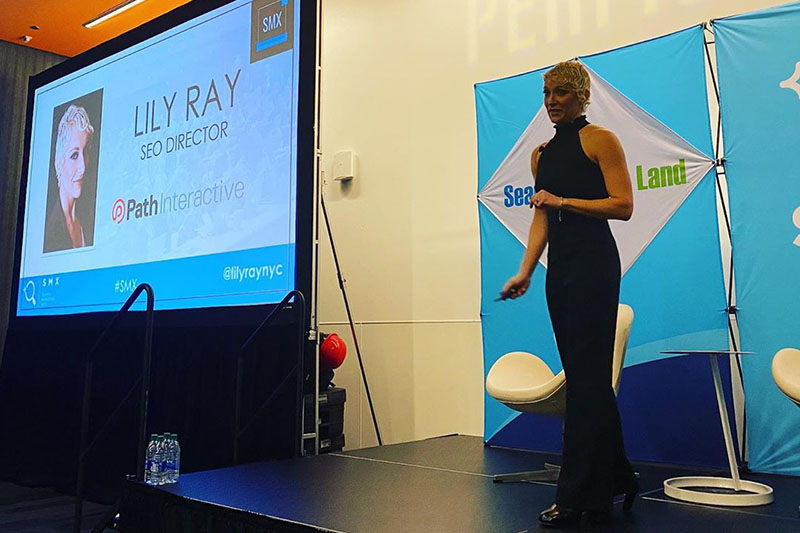 Lily Ray speaking onstage at an SMX search marketing conference