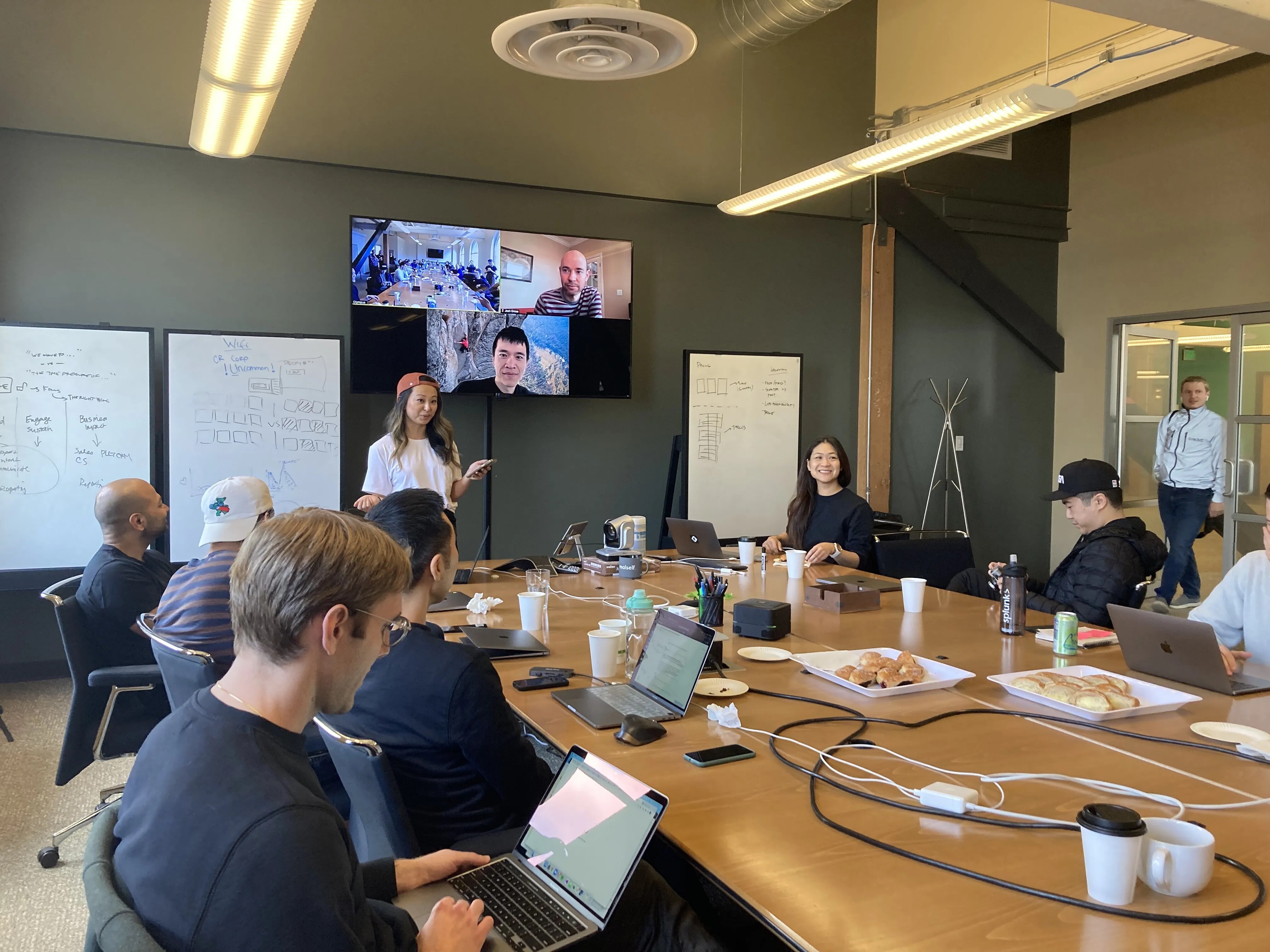 Linda Lian standing and speaking during a Common Room team meeting around a large conference table