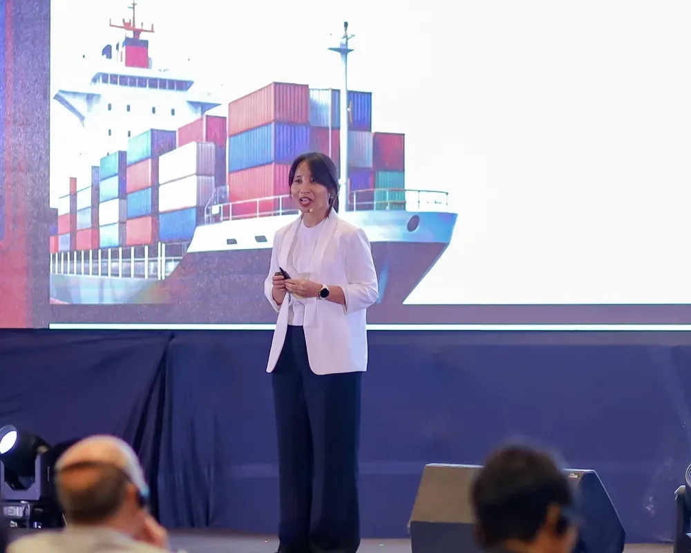 Liris Maduningtyas presenting at Shrimp Outlook 2026 beside a projected cargo ship