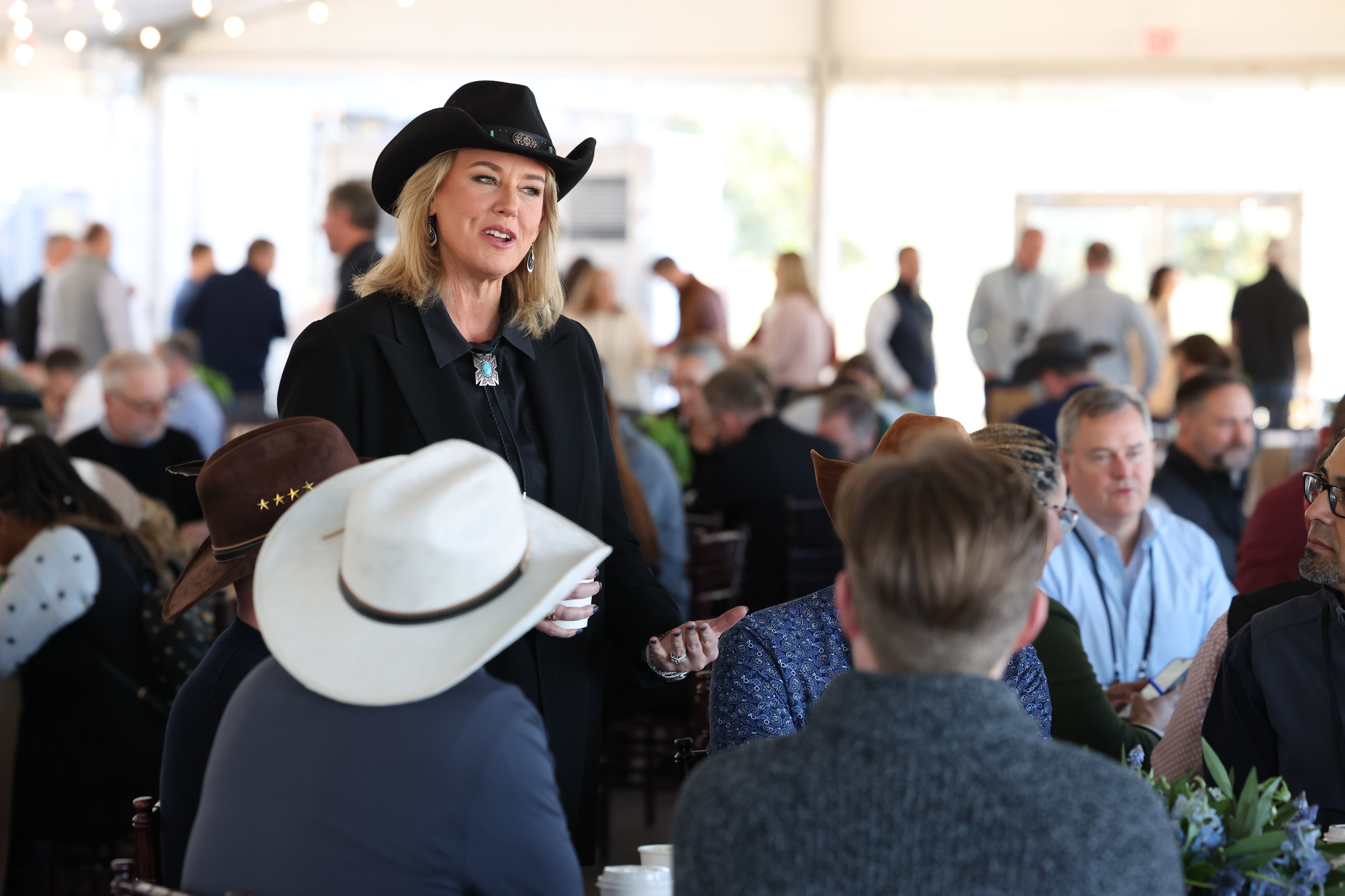 Lisa Atherton wearing a black cowboy hat and speaking with people seated at an event