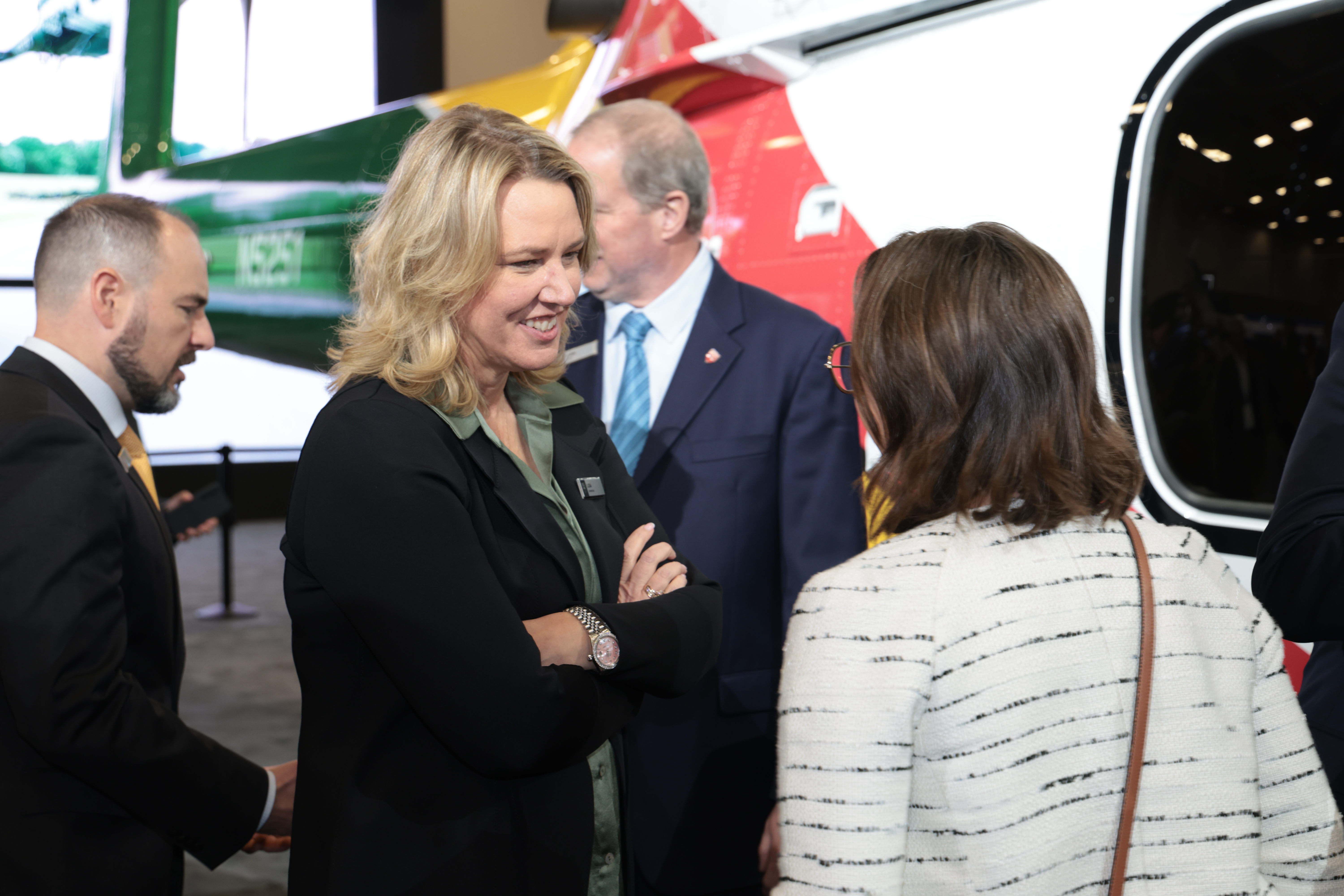 Lisa Atherton talking with attendees beside a helicopter on display