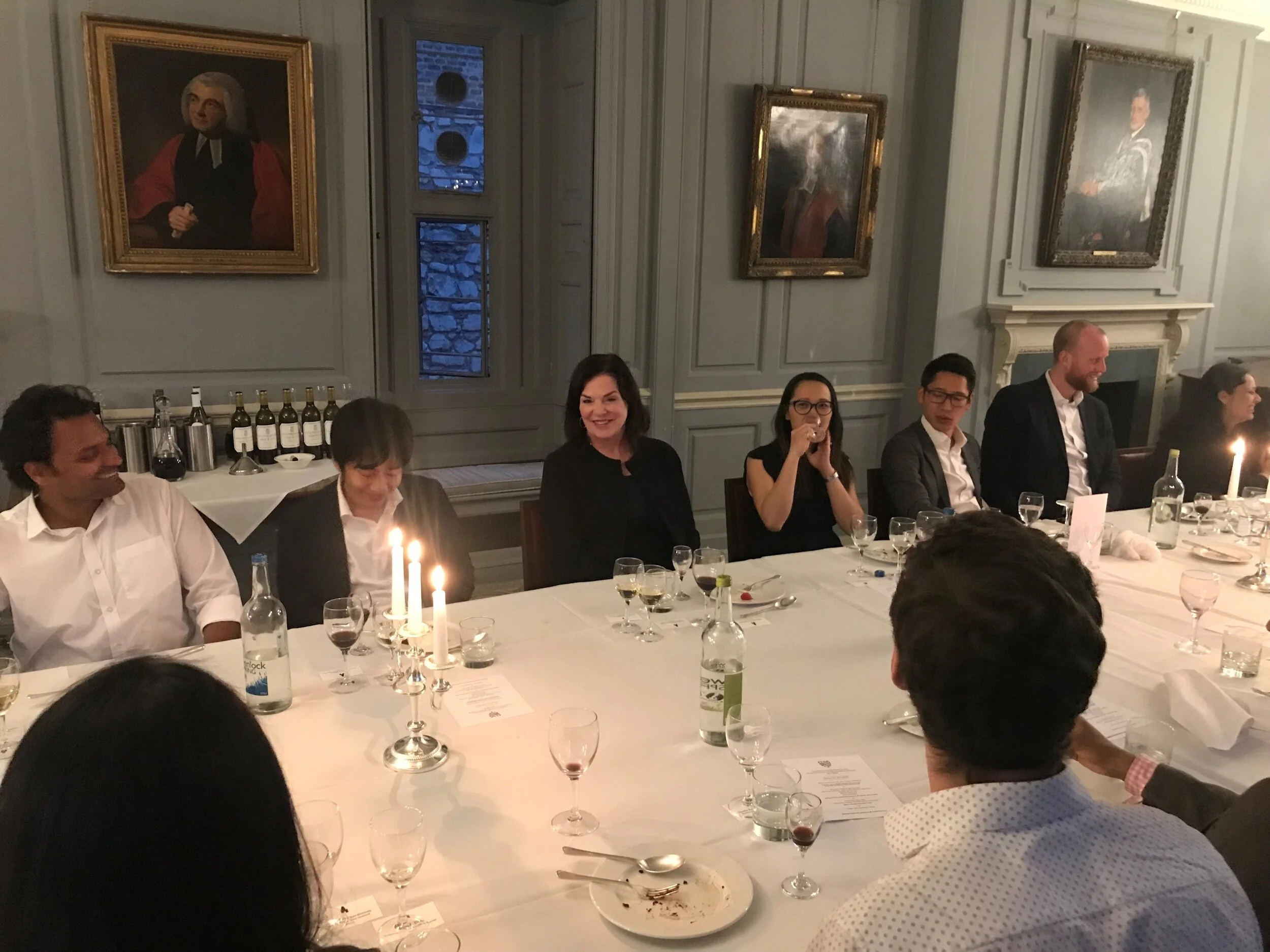 Lisa Drakeman seated with MBA students around a candlelit dinner table at Gonville and Caius College, Cambridge