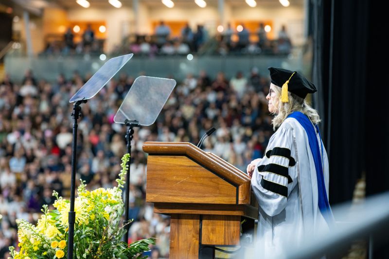 Lisa Grow in academic regalia addressing University of Idaho graduates from a lectern