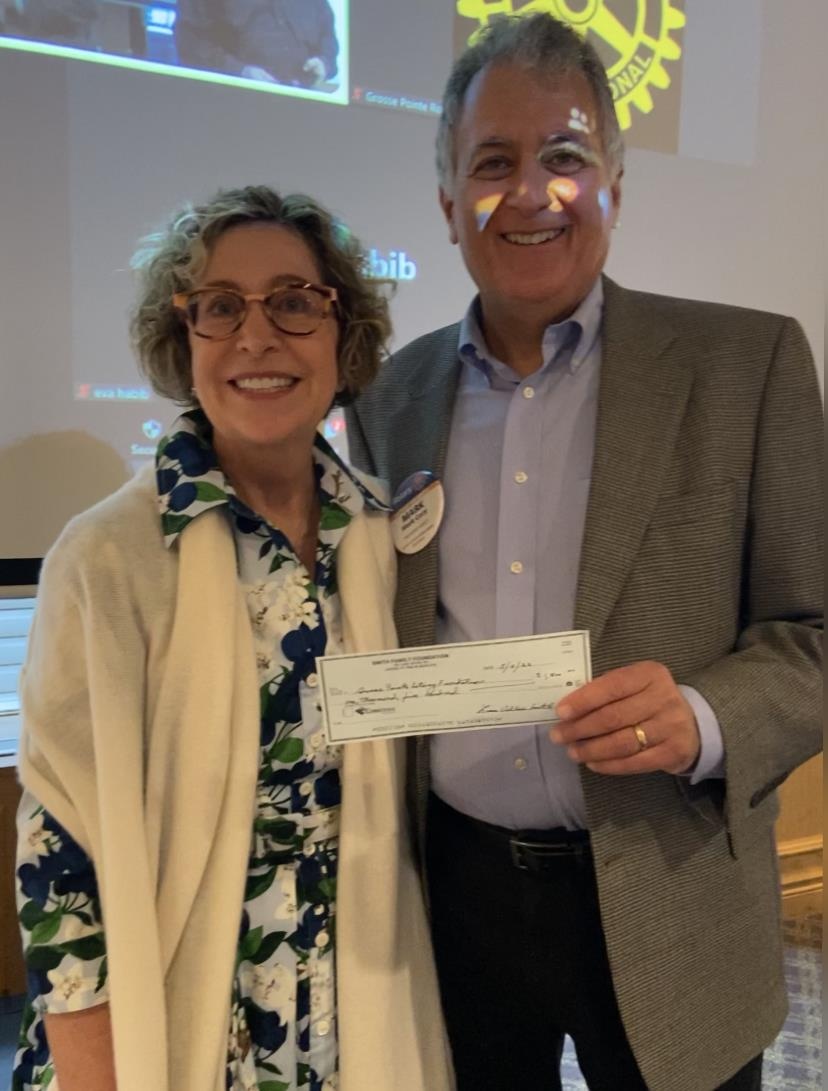 Lisa Vallee-Smith at a Grosse Pointe Rotary gathering, standing beside a man holding a donation check