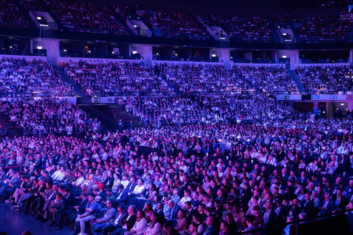 Web Summit attendees gathered under purple lighting inside the Lisbon venue
