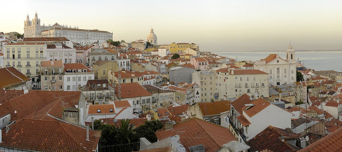 A sunlit view across the tiled roofs and compact streets of Alfama in Lisbon