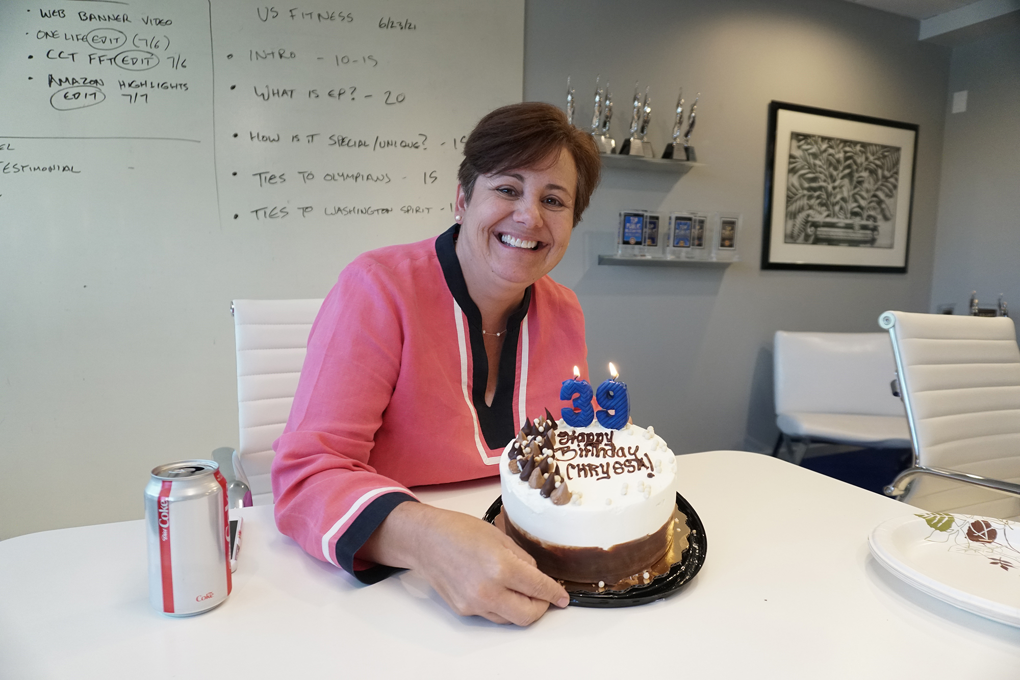 Live Wire founder Chryssa Zizos smiling beside a birthday cake in a conference room