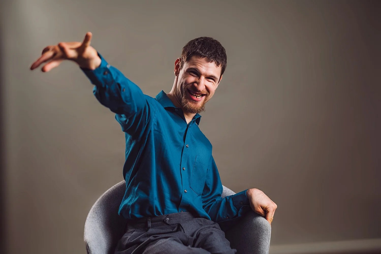 A smiling man in a blue shirt reaches toward the camera during a Living in the Light portrait session