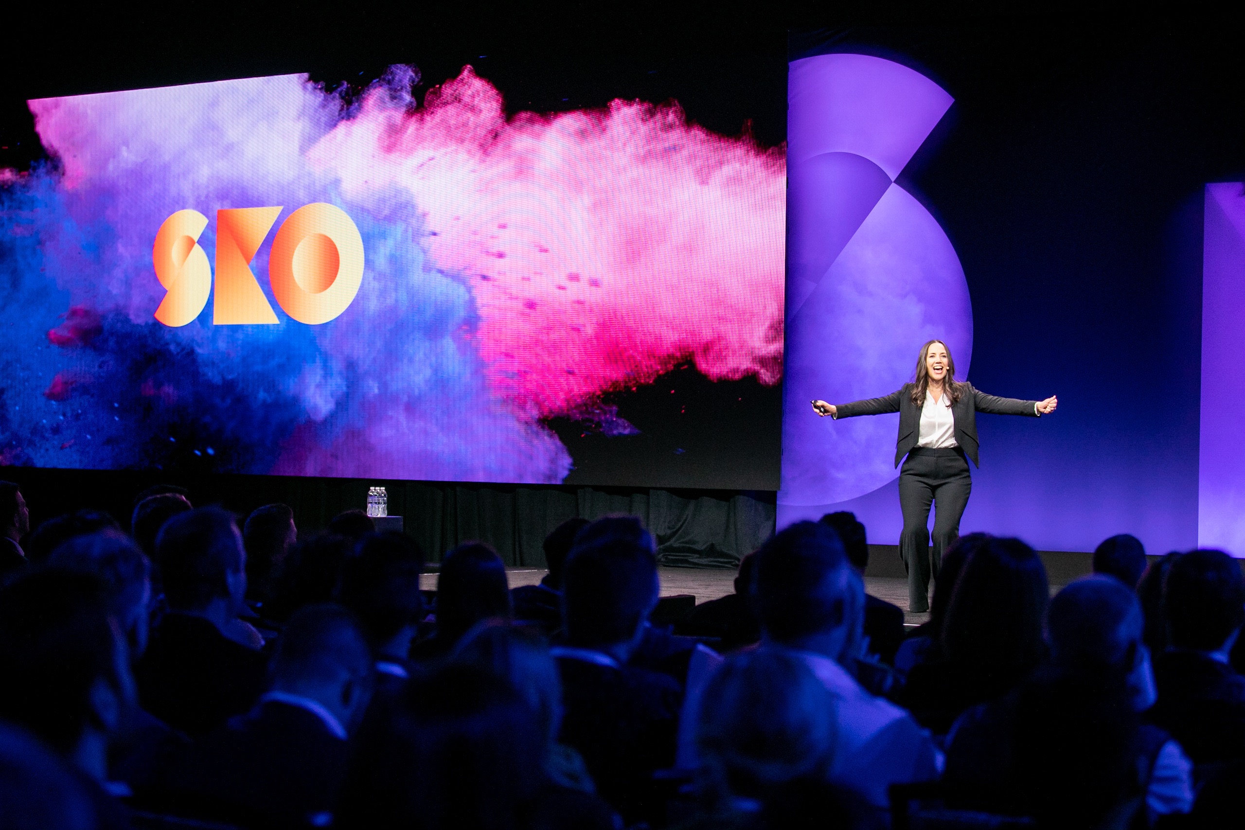 Liz Kokoska speaking onstage before a large audience