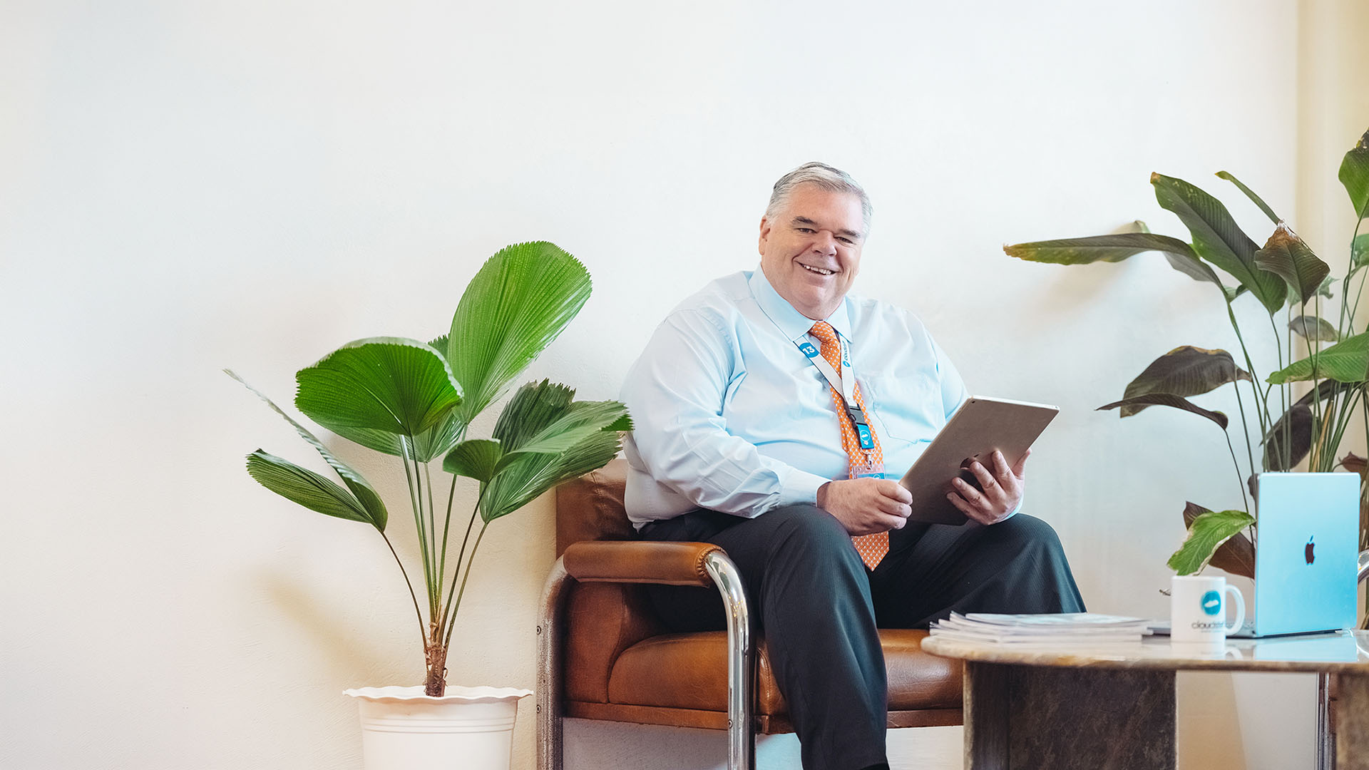 Lloyd Ernst seated in a chair with a tablet beside a laptop