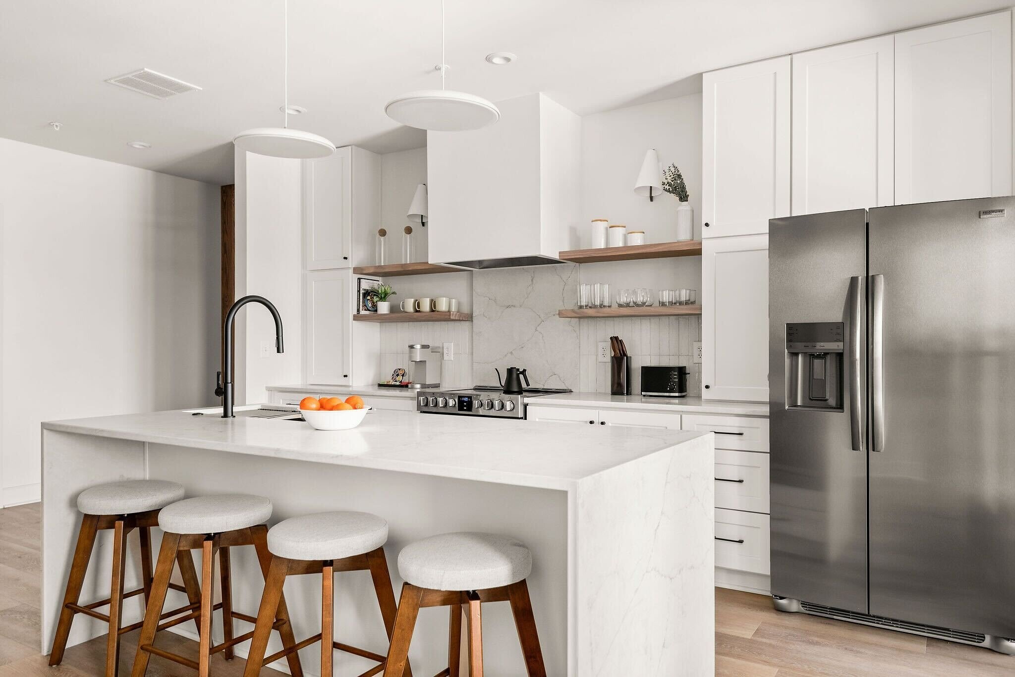Full kitchen with white cabinetry and a dining island at The Eighteen by Locale