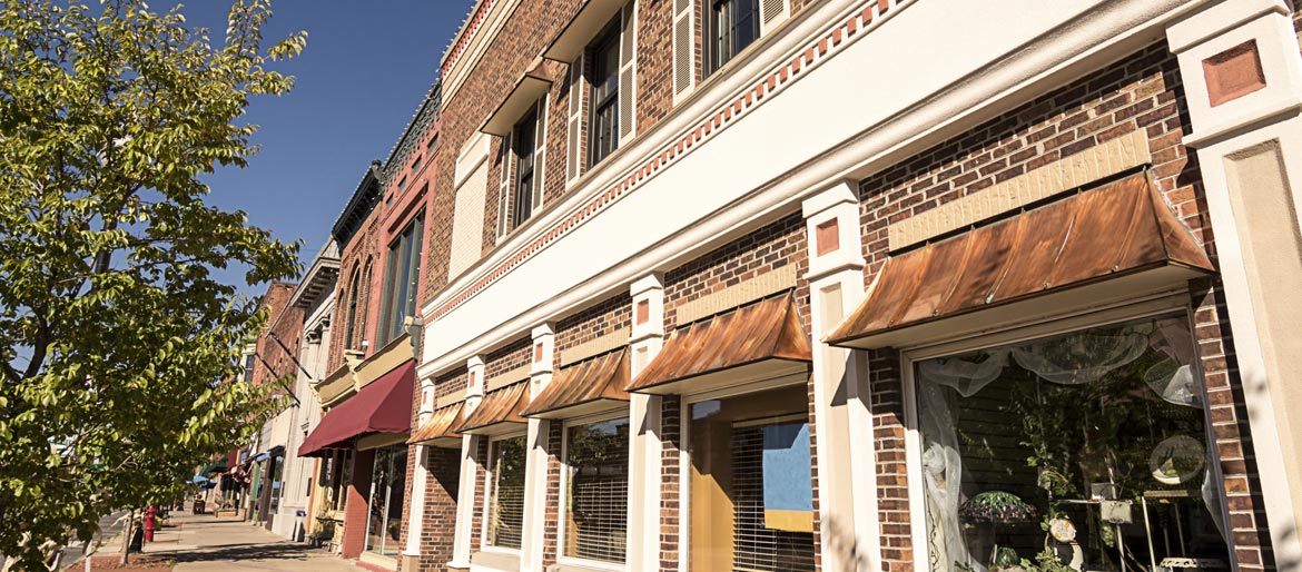 Brick storefronts and shaded shop windows along a traditional Main Street