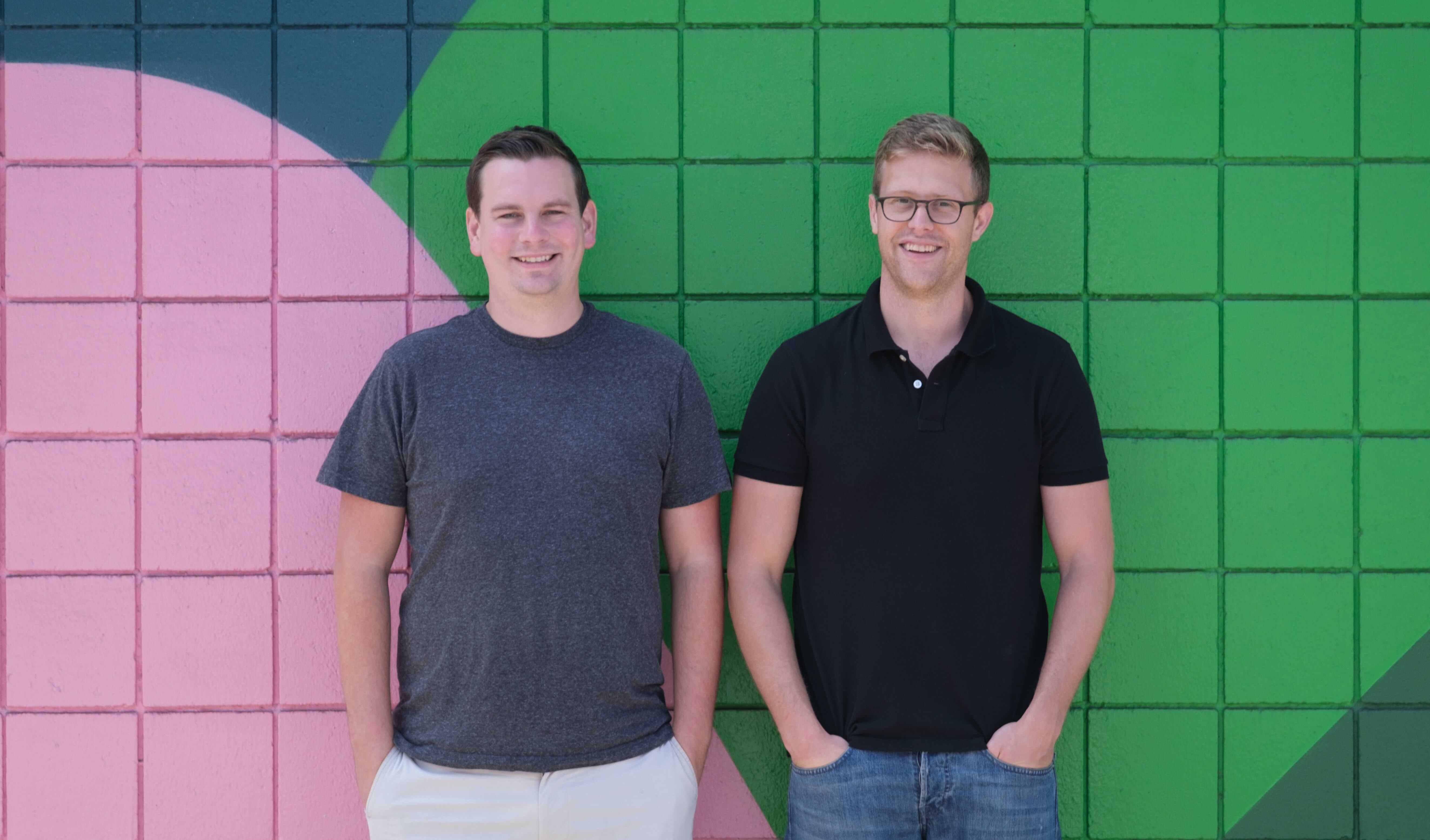 Logan Head and Grant LaFontaine standing in front of a colorful geometric wall