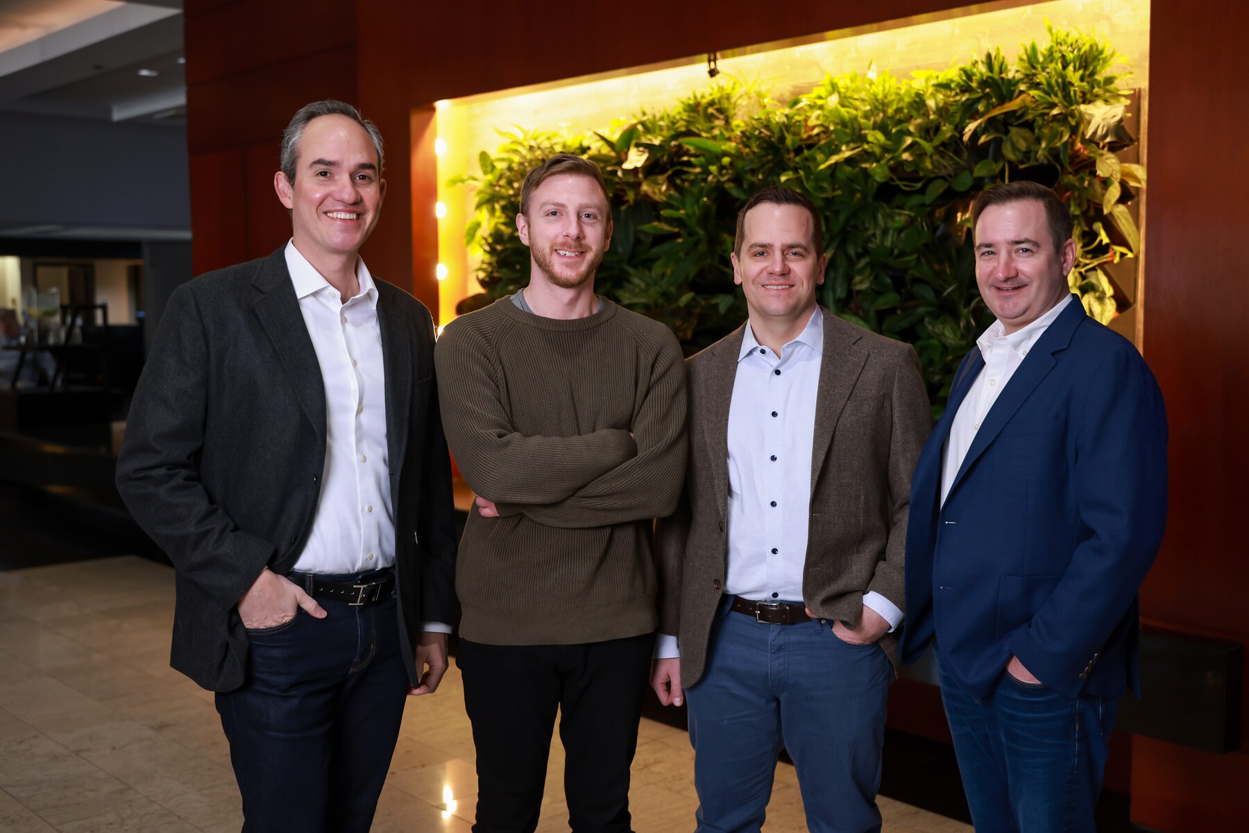 LogicGate leaders standing together in front of a living plant wall