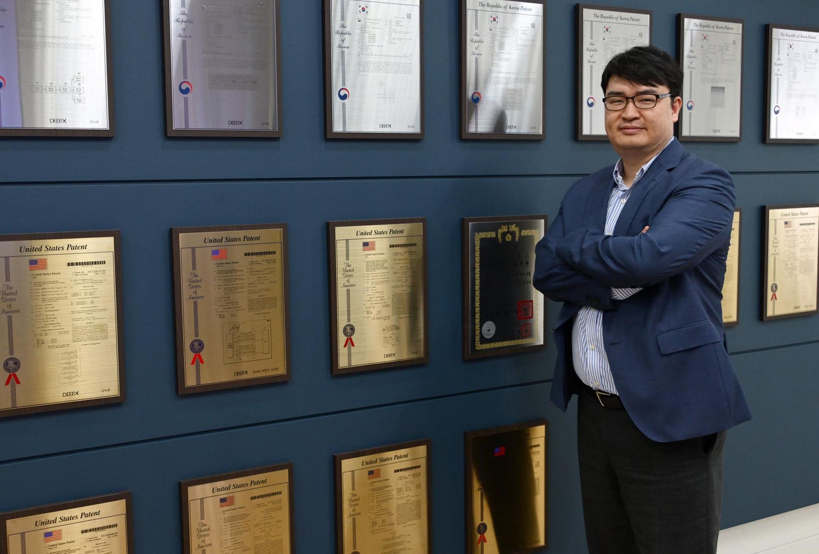 Lokwon Kim standing in front of a wall displaying DEEPX patent plaques