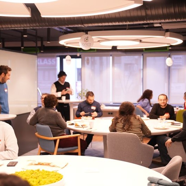 People talking and sharing a meal around tables in Lonca’s shared space
