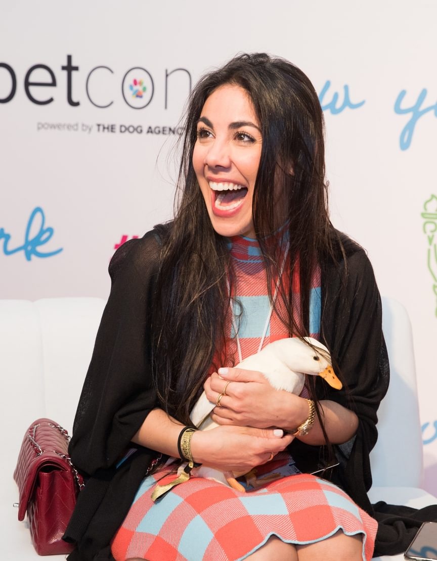 Loni Edwards seated at PetCon, smiling while holding a white duck