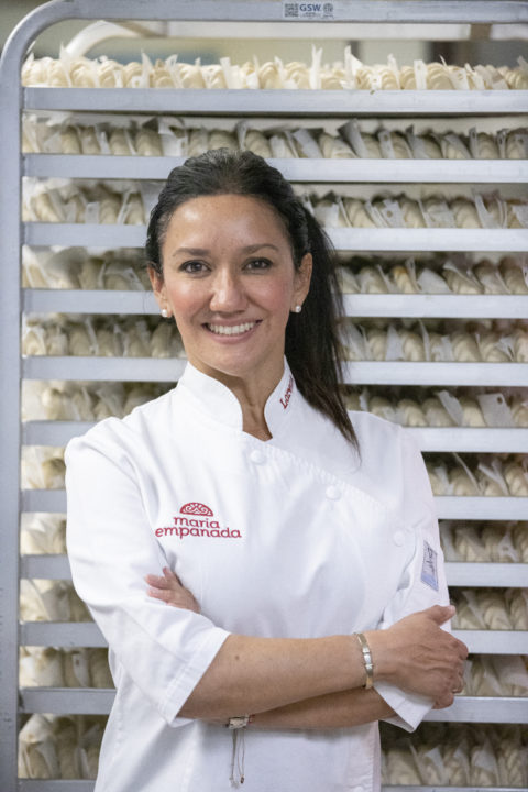 Lorena Cantarovici standing in a Maria Empanada kitchen in a white chef coat