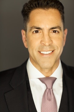 An archival press portrait of Lorenzo Esparza in a dark suit and pale pink tie