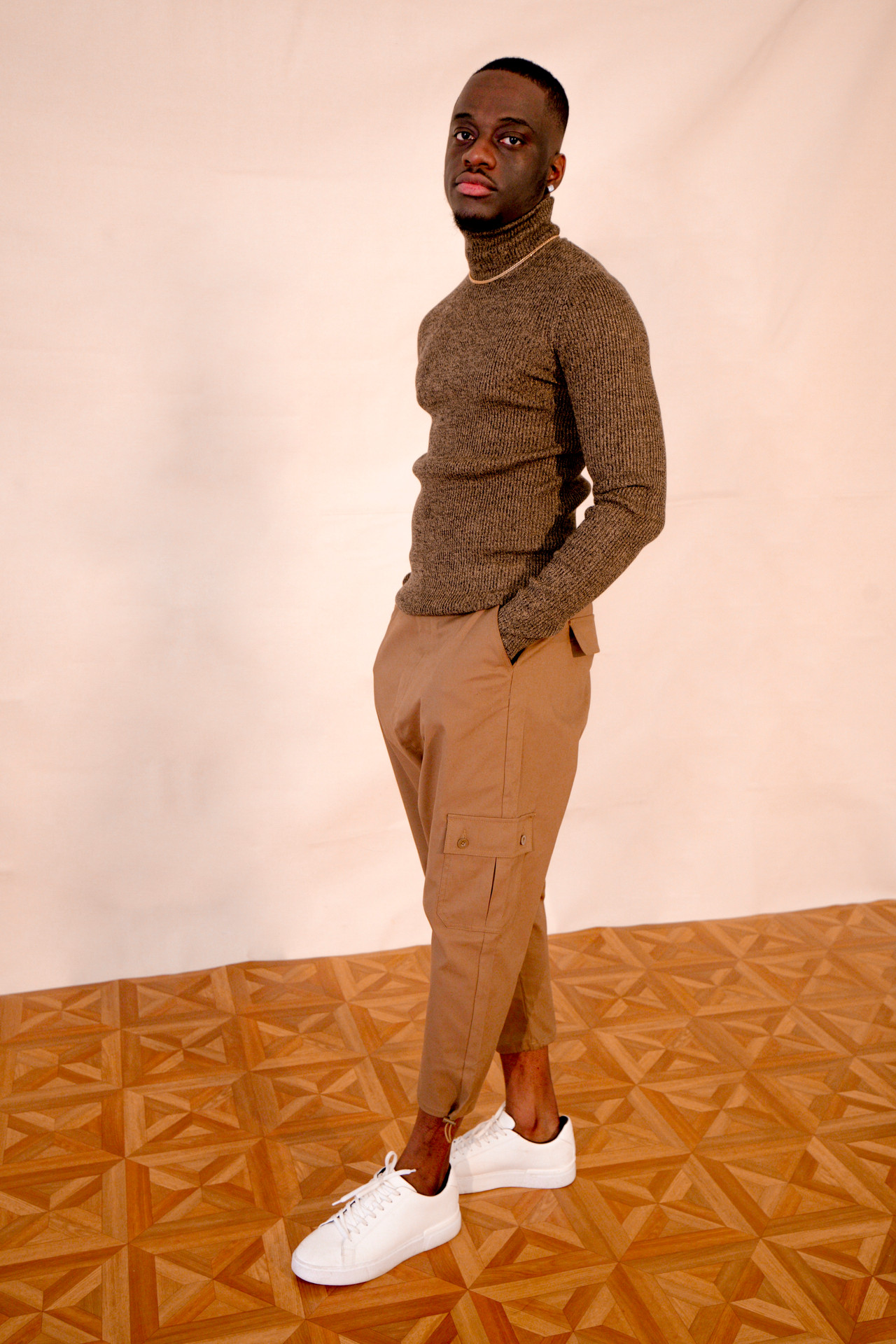 Lotanna Ezeike standing in a brown roll-neck and tailored trousers during a 2021 editorial shoot