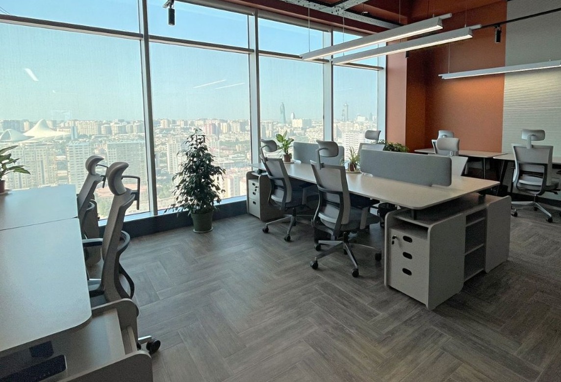LTC workspace with divided desks, ergonomic chairs and large windows overlooking Baku