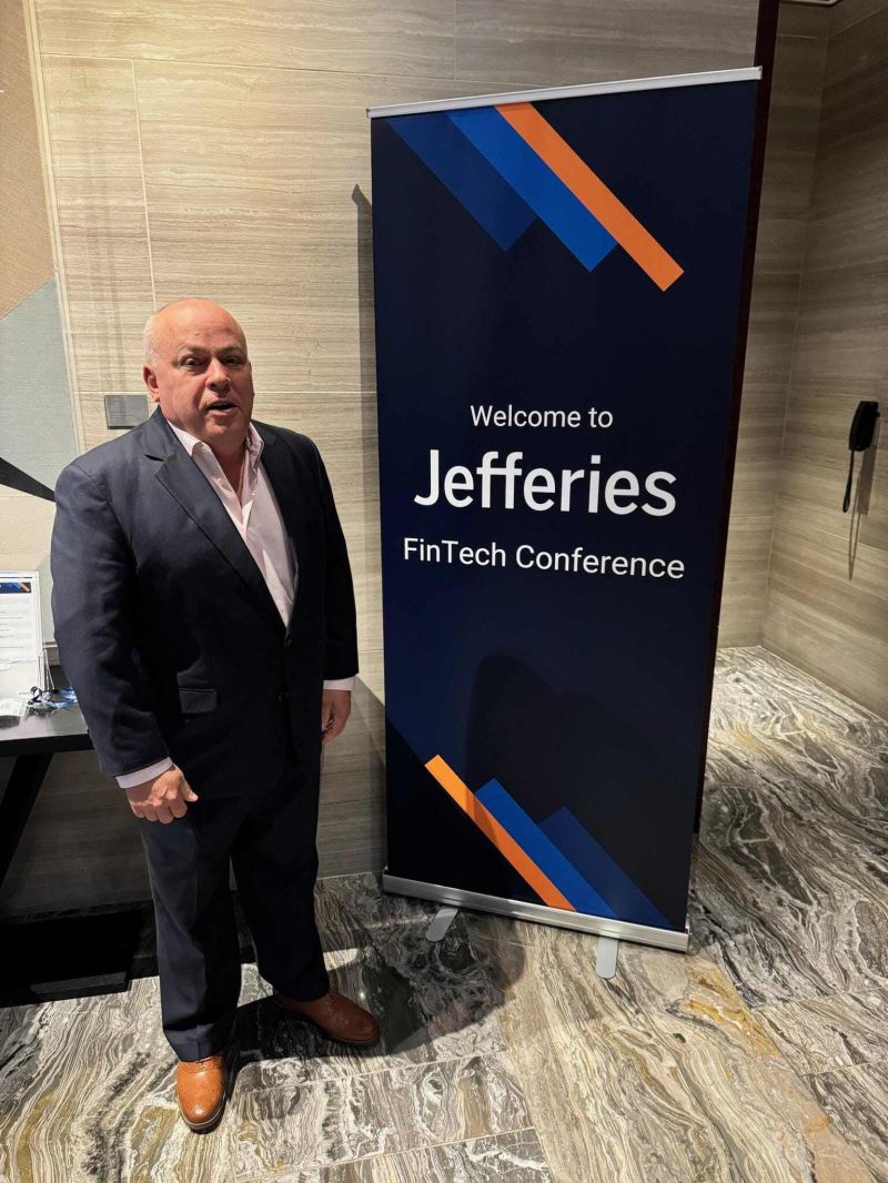 Louis Hoch standing beside the Jefferies FinTech Conference banner