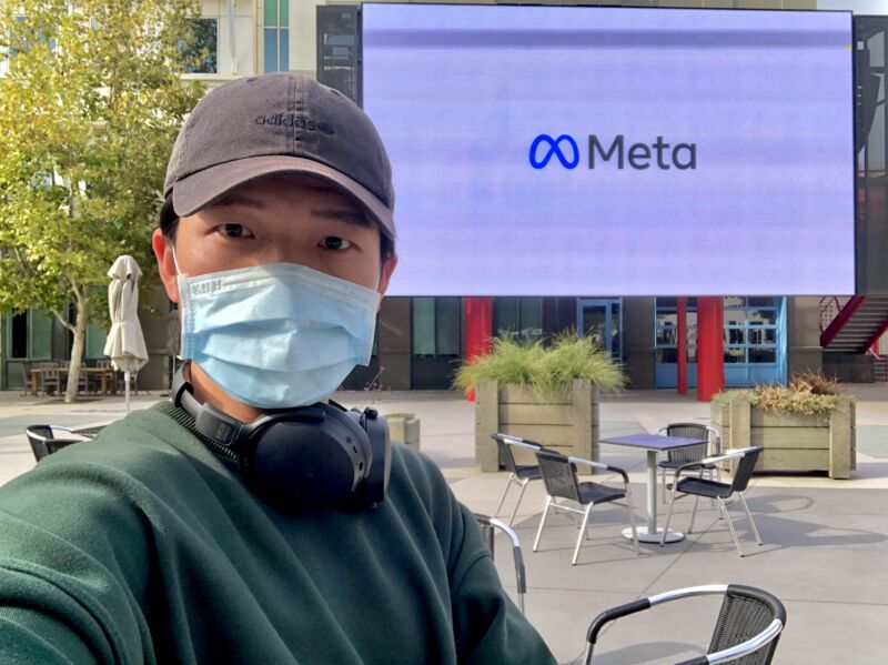 Louis Lee seated outside a Meta office, wearing a cap, headphones and a face mask