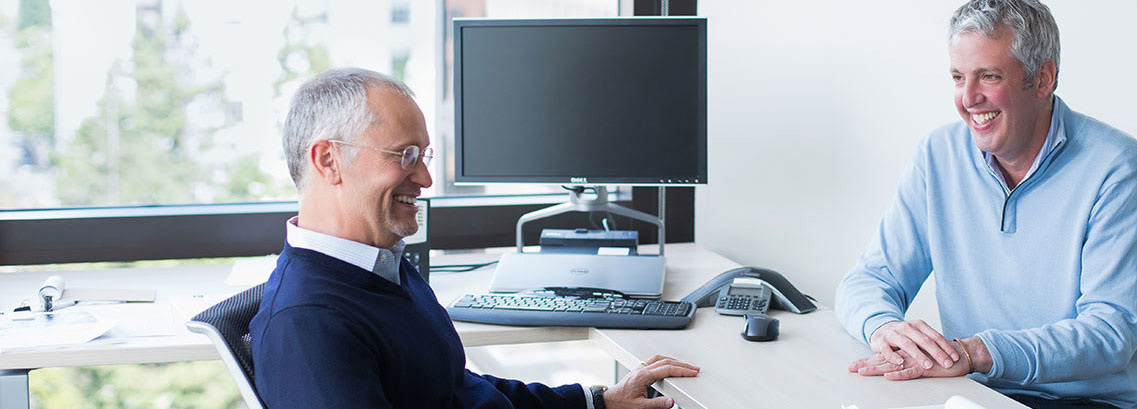 LiveVox co-founders Louis Summe and Larry Siegel talking across an office desk