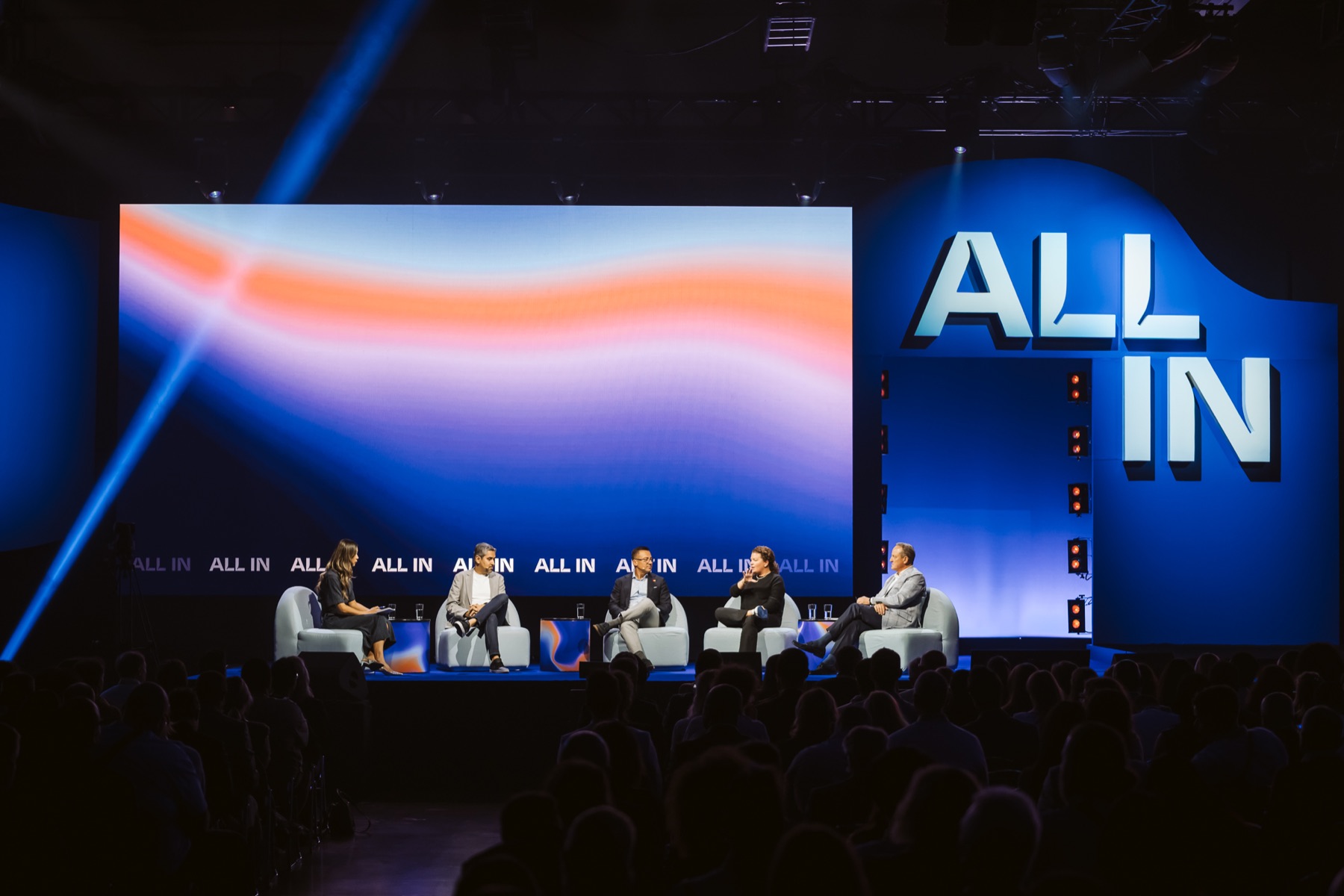 Five speakers seated on the ALL IN stage in Montreal, with Louis Têtu at the right