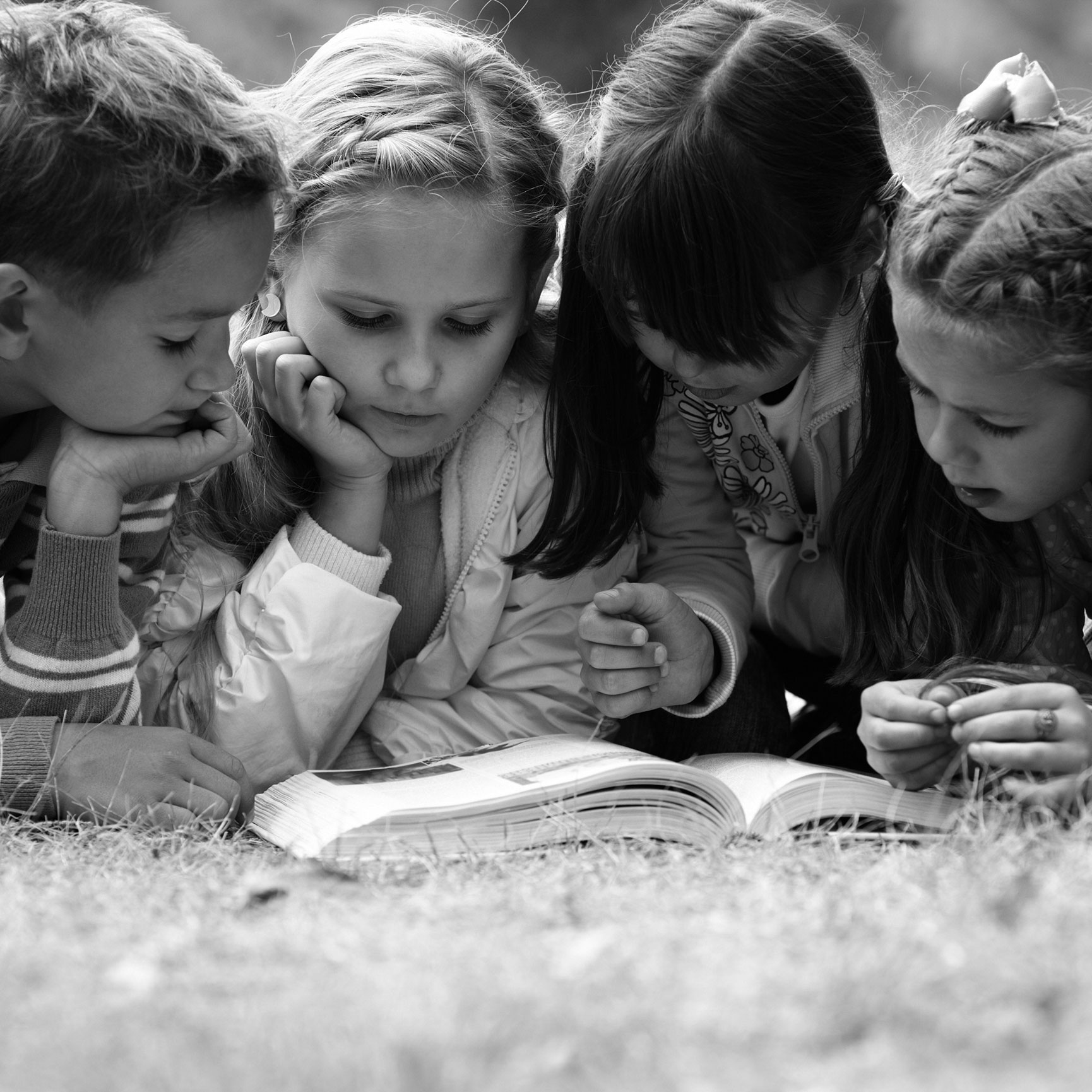 Four children gathered around an open book