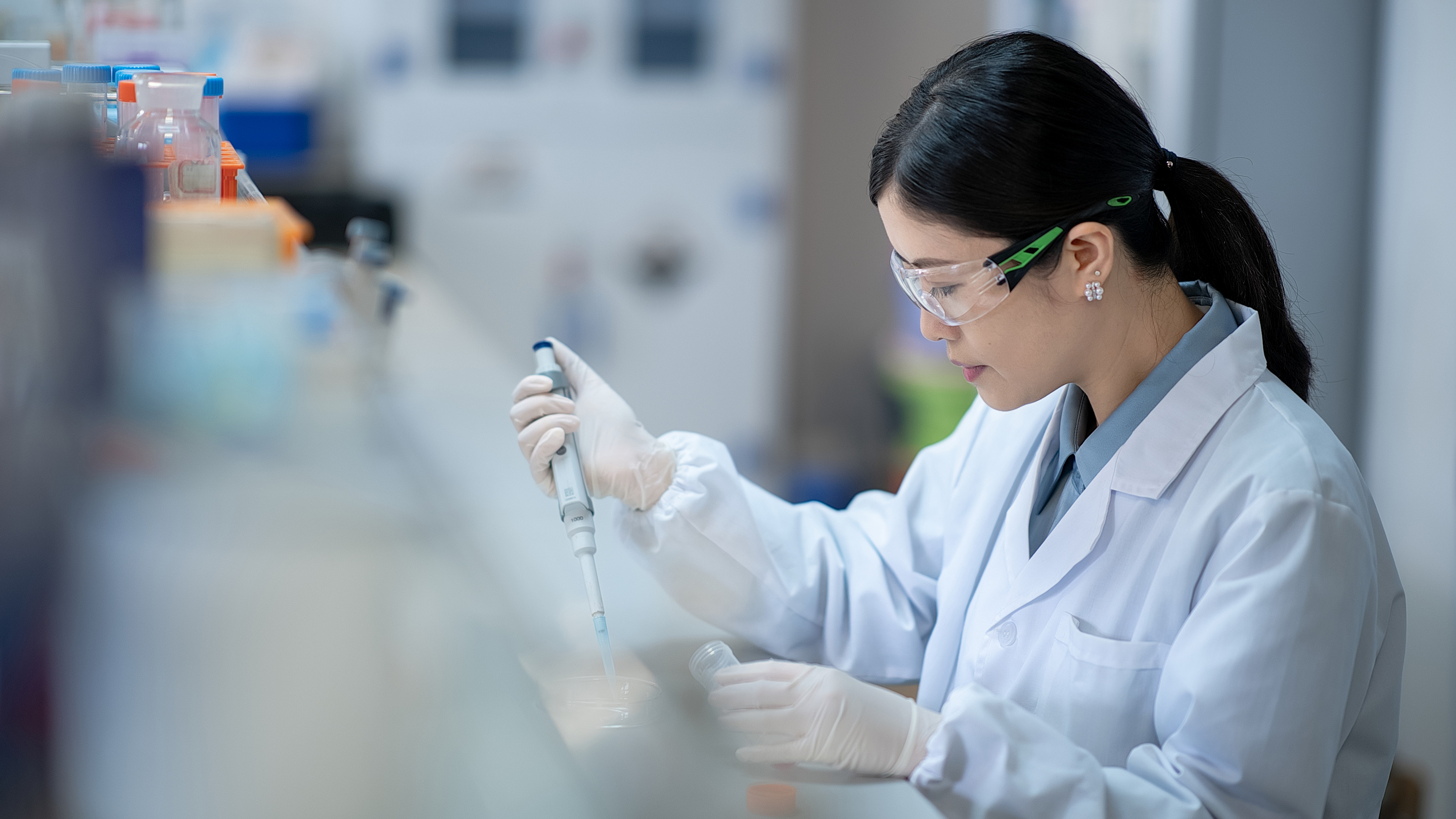 A Lucence laboratory scientist pipettes a sample at a workbench