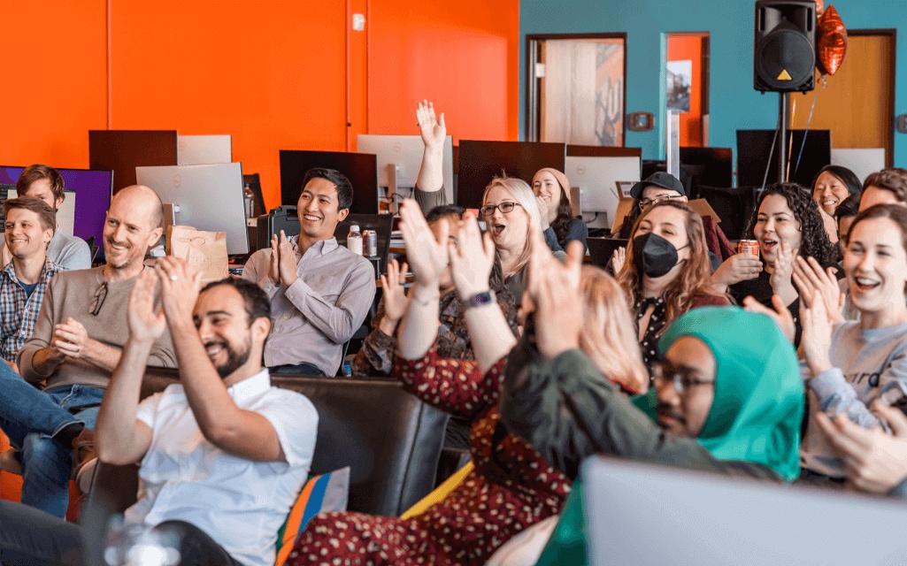 Osmind team members seated together, applauding at a company gathering