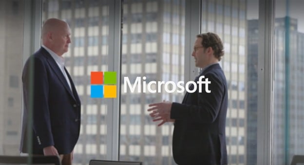 Two Microsoft representatives speaking in an office, with the Microsoft logo overlaid