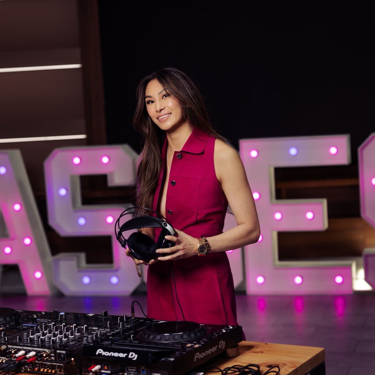Lucy Guo standing behind a DJ console at a Passes event