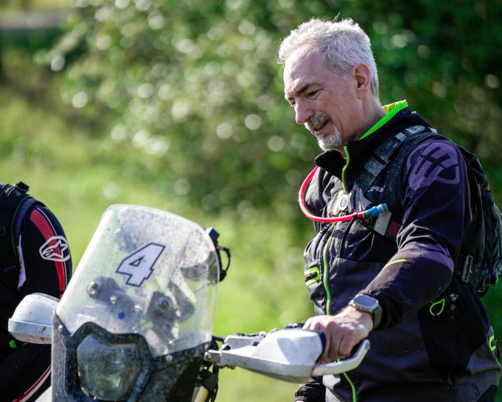 Luigi Costa in motorcycle riding gear beside a motorcycle