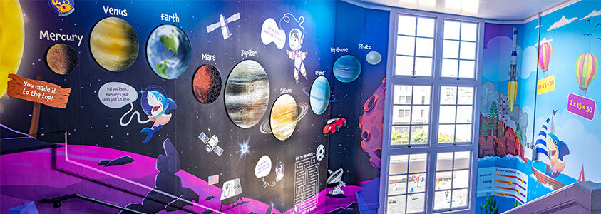 Colorful space-themed printed graphics across Sherman Elementary School stairwell walls