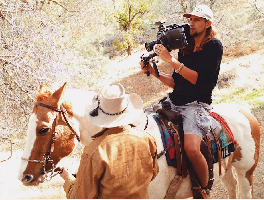 Lukas Colombo operating a camera while seated on a horse outdoors