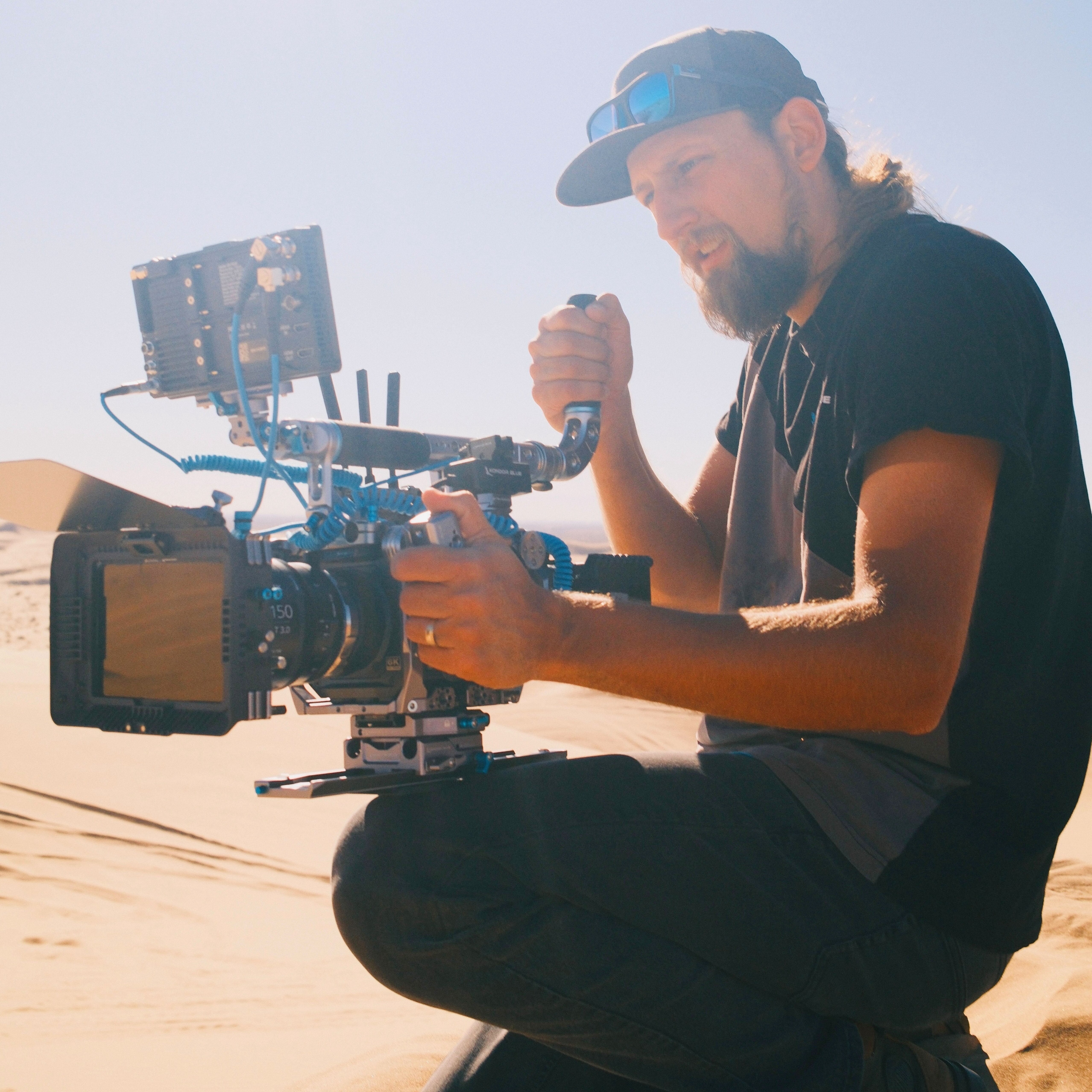 Lukas Colombo working with a cinema camera rig outdoors in a sandy landscape
