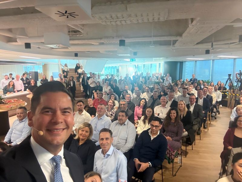 Luke Billiau wearing a headset microphone in front of colleagues at JLL’s ANZ town hall