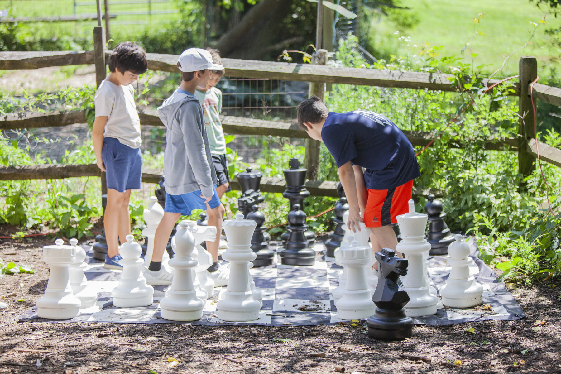 Children moving oversized chess pieces outdoors at iCAMP