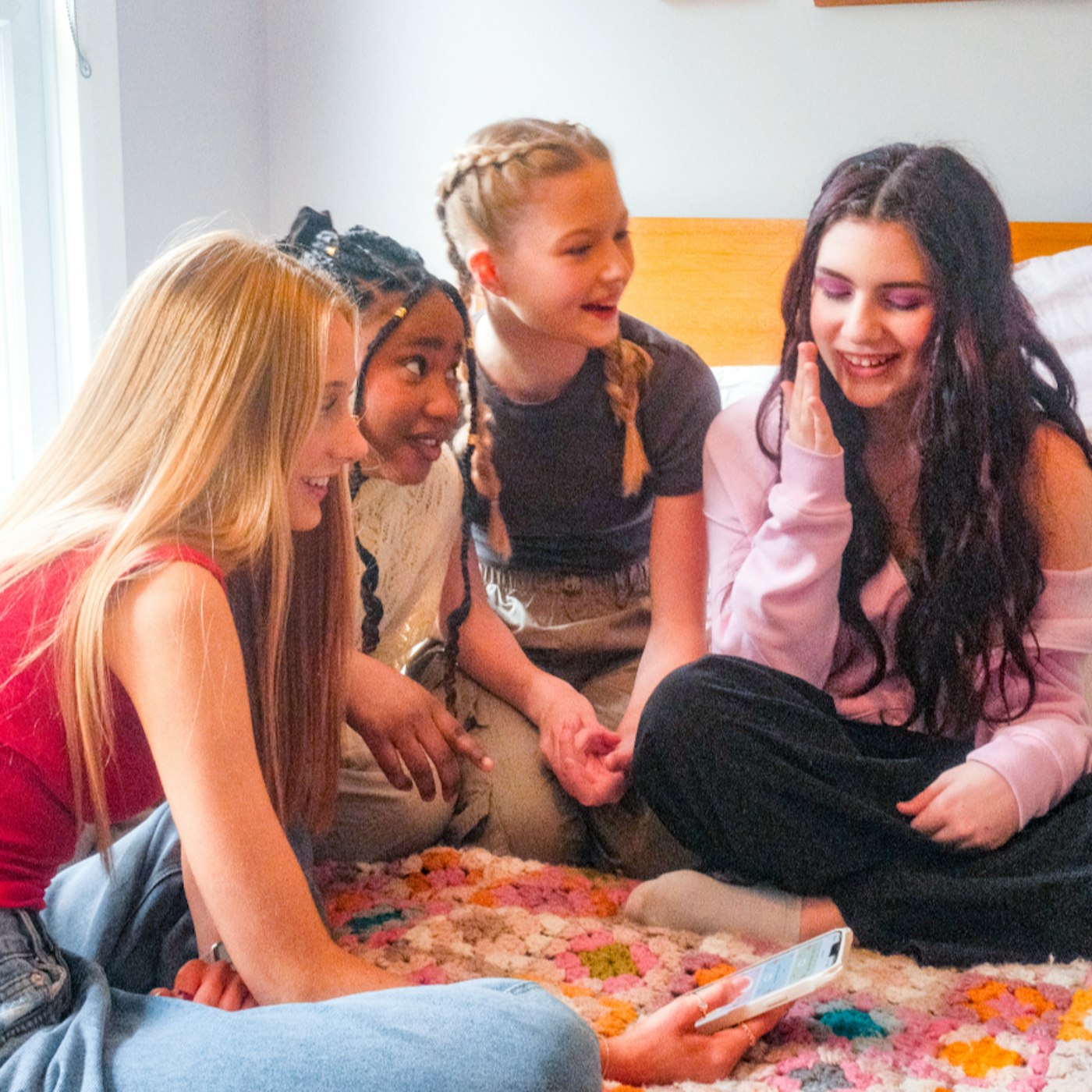 A group of teenagers gathered around a phone showing luna