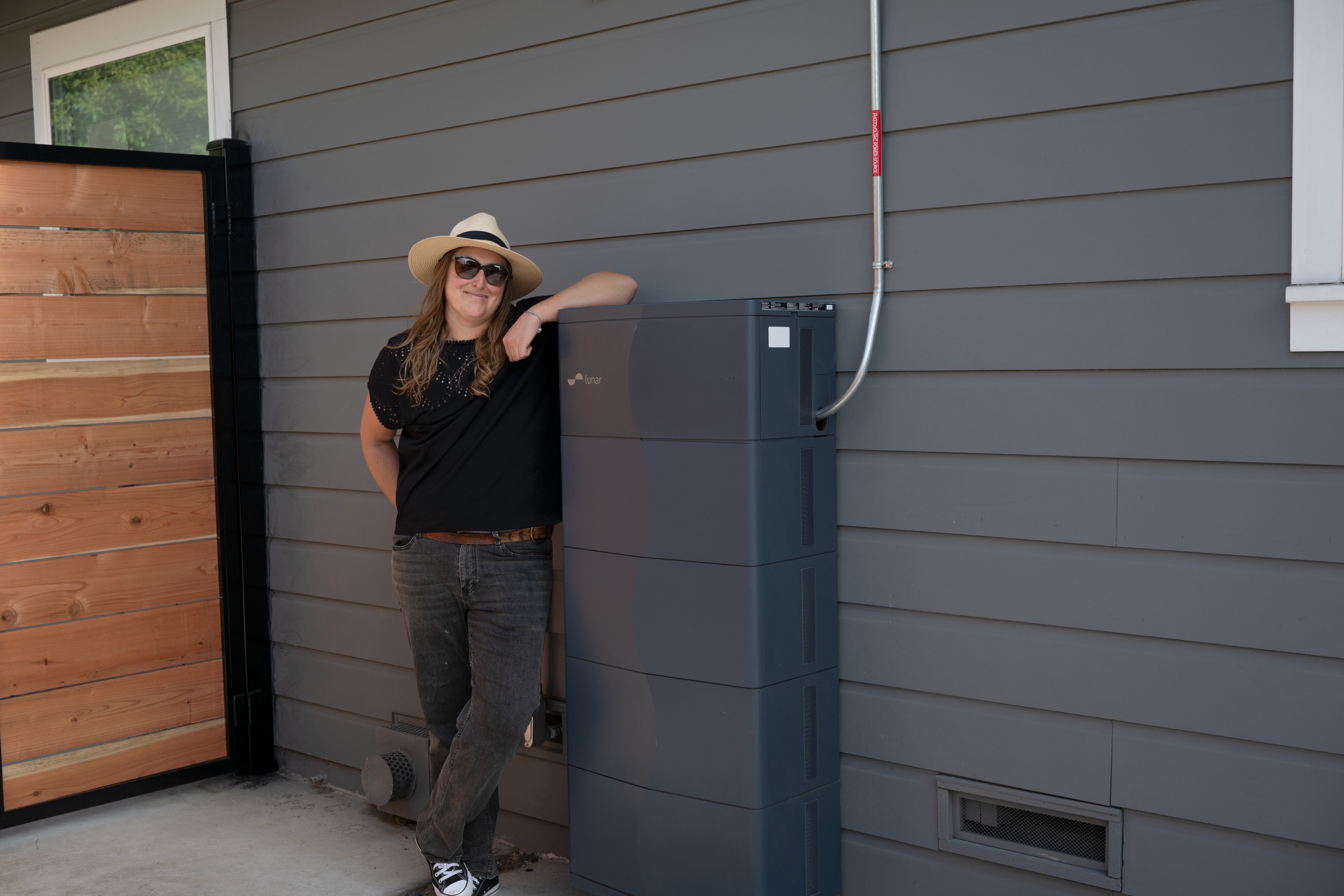 Lunar customer Amber Lucas stands beside a home battery