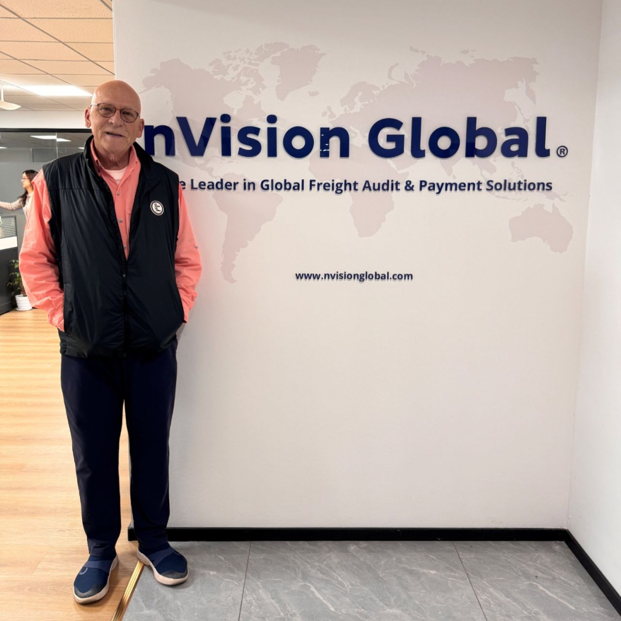 Luther M. Brown standing beside the nVision Global sign and world map during his Ningbo team visit