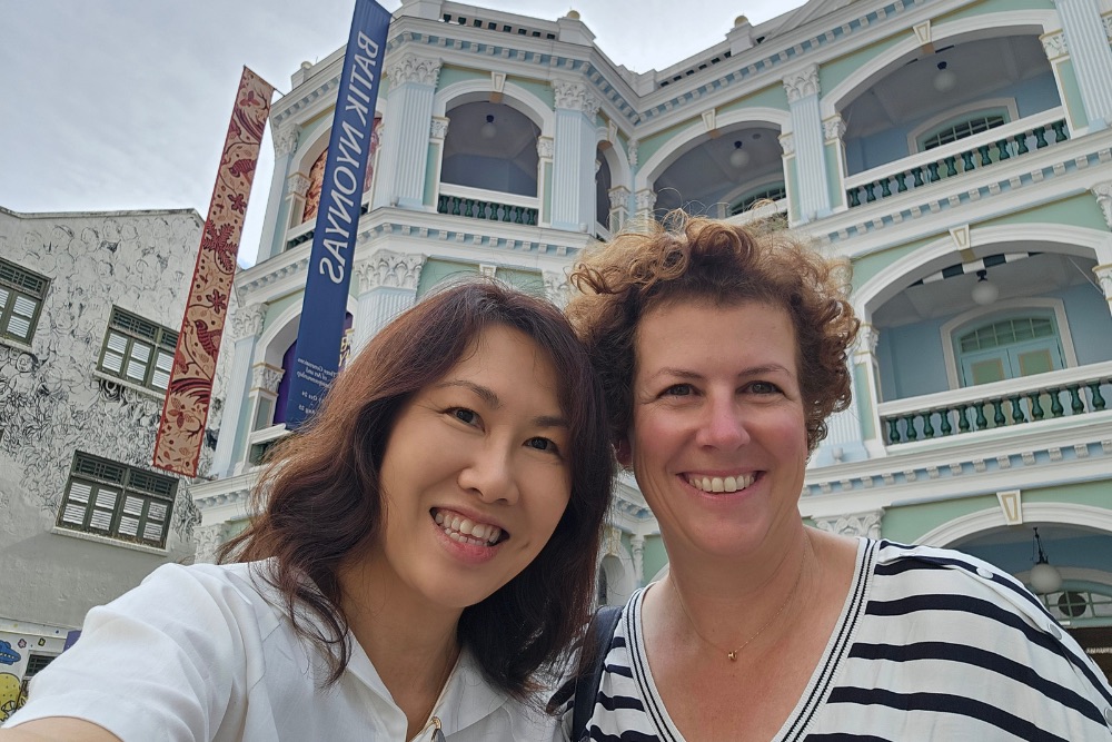 Lynne Lim, left, and Cécile Réal smiling together outside an ornate building