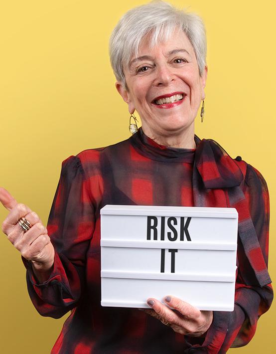 Founder Margi Booth holding a lightbox that reads Risk It