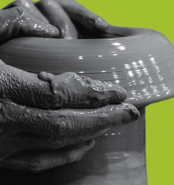 Hands shaping a clay vessel against a bright green background